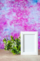 Vertical view of empty picture frame standing on table and flower on pink blue marble background