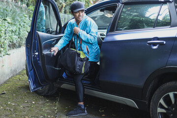 Asian male getting out of the car with sport bags prepare for workout training