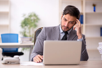 Young male employee and too much work in the office