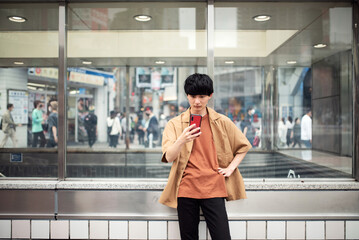 渋谷で待ち合わせをする若い男性 - obrazy, fototapety, plakaty