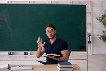 Young male teacher sitting in the classroom