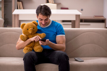 Young man with toy bear at home