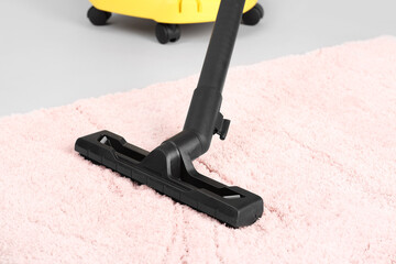 Vacuum cleaner with carpet on grey background, closeup