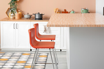 Interior of modern kitchen with bar stools near table