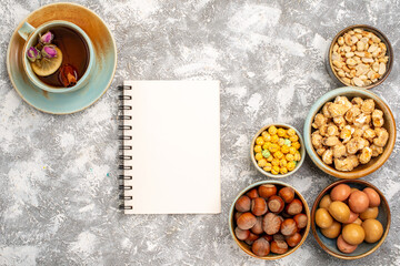 top view cup of tea with nuts notepad and candies on white background nut tea candy snack
