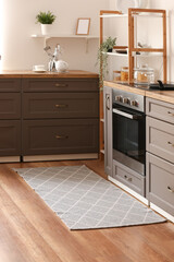 Stylish grey rug on floor in kitchen