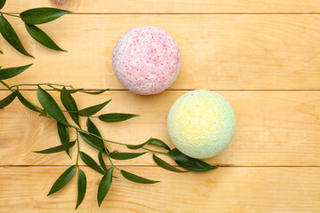 Bath bombs with plant branches on wooden background
