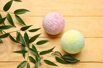 Bath bombs with plant branches on wooden background