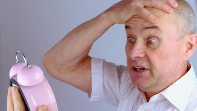 close-up mature man, senior 60 years old holds alarm clock in hand, concept missing time, oversleeping important meeting, life deadline, active SeniorLife, old age crisis, decrease in overall activity