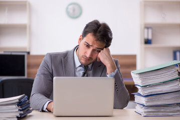 Young male employee unhappy with excessive work in the office