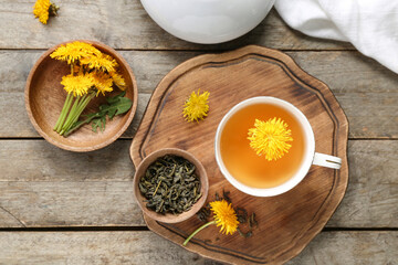 Board with bowl and cup of healthy dandelion tea on wooden background