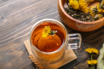 Bowl and glass cup of healthy dandelion tea on wooden background