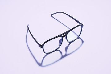 Modern black eyeglasses on pale purple background