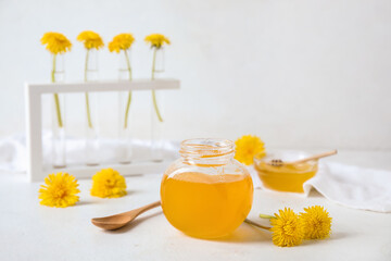 Jar and bowl with dandelion honey on white table