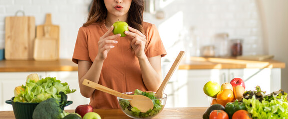 Fototapeta na wymiar Portrait of beauty body slim healthy asian woman having fun cooking and preparing vegan food healthy eat with fresh vegetable salad, apple in kitchen at home.Diet concept.Fitness and healthy food