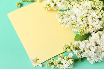 Yellow blank card and lilac flowers on turquoise background