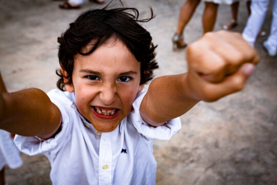 A handsome excited boy fist-pumping at a party with some missing teeth looking directly at the camera.