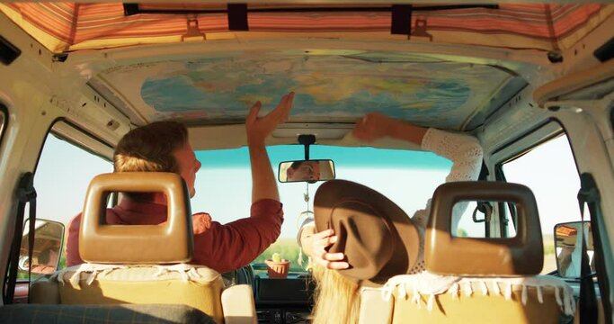 young couple looking at map, talking about future trip, travel, dreams. Summer trip friends planning camper van holiday pointing finger at map rear view, vacation adventure, journey, travel lifestyle