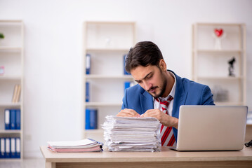 Young male employee and too much work in the office