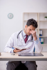 Fototapeta premium Young male doctor reading book in the clinic