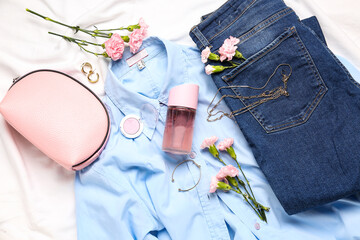 Composition with female accessories, cosmetics, clothes and carnation flowers on light fabric background, closeup