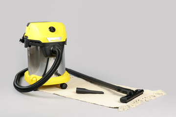 Fototapeta premium Vacuum cleaner with rug on grey background