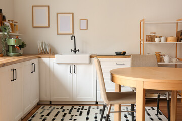 Interior of stylish kitchen with white counters, dining table and chairs