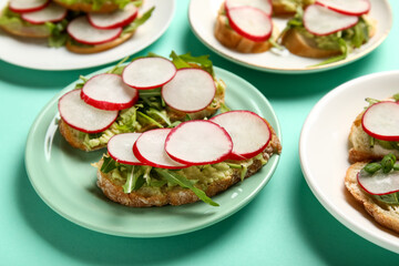Plates with delicious radish bruschettas on turquoise background