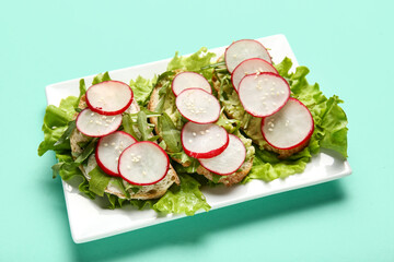 Plate with delicious radish bruschettas on turquoise background