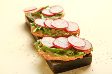 Board with delicious radish bruschettas on beige background