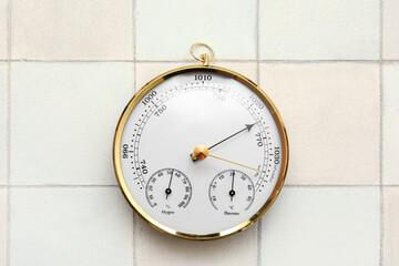 Aneroid barometer on white tiled background