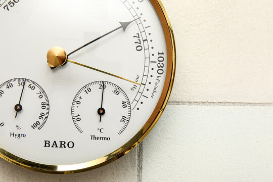 Aneroid barometer on white tiled background