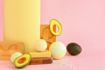 Bath bombs and avocado on pink background