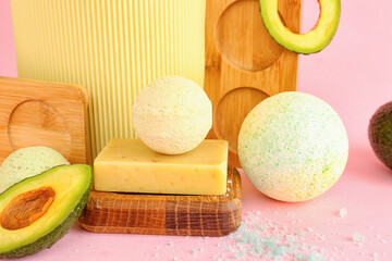 Bath bombs and avocado on pink background