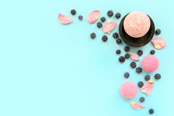 Bath bomb with blueberry and floral petals on blue background