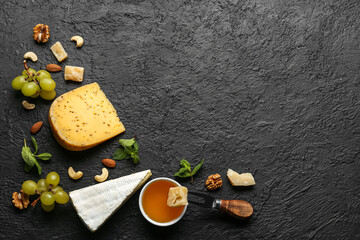 Frame made of tasty cheese, nuts, grapes and honey on dark background