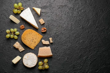 Fototapeta na wymiar Different types of tasty cheese, nuts and grapes on dark background