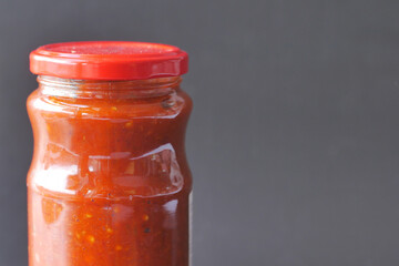 chili tomato sauce in a small jar against black background 