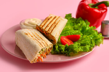 Plate with tasty shawarma and lettuce on pink background