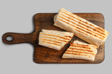 Board with tasty shawarma on grey background