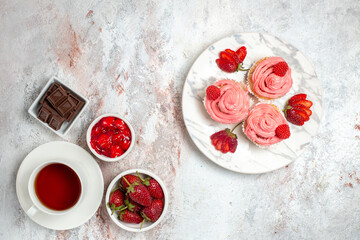 top view pink strawberry cakes with cream and cup of tea on white desk fruit tea cake biscuit sweet cookie