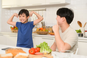 Asian boy showing strong arm , playful with his father in home