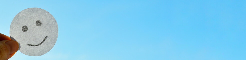 Smiley from white paper on blue sky background. World Day of Peace. Day Against Humiliation....