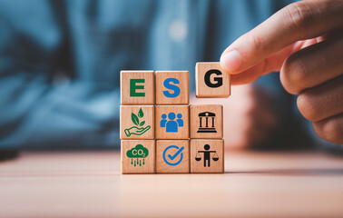 Businessman assemble ESG wording on wooden cube block for sustainable organization development and...