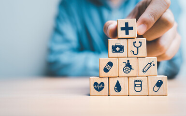 Businessman  hand stacking  healthcare icons on wooden block cube for health insurance and life assurance concept.