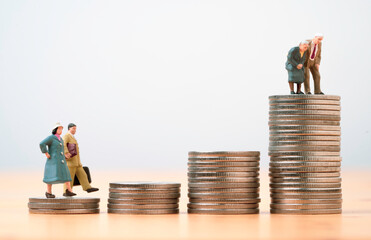 Miniature figure young man and woman walk and Couple Senior Pensioners standing on the top coins...