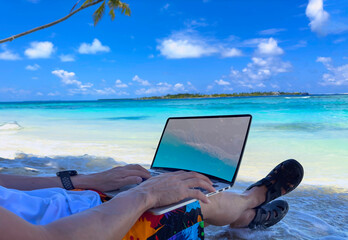 Nomad digital with laptop and running remotely with bright scenic view near poolside on the beach in summer time