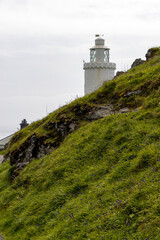 Fototapeta na wymiar Lighthouse with down and hillside against a plane sky