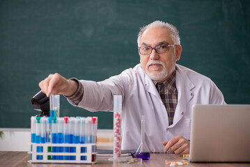 Old male teacher chemist sitting in the classroom