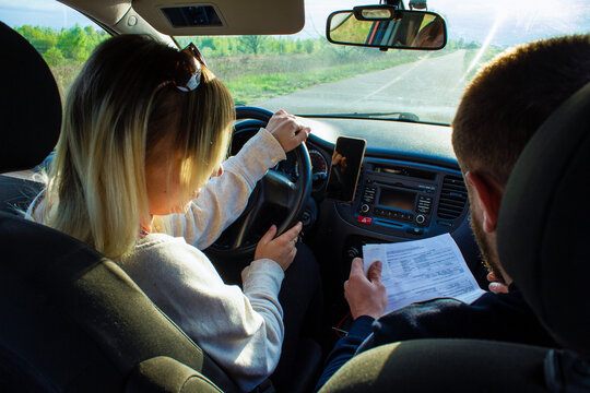 A driving instructor explains to a female student the rules for driving a car. A woman takes a driving test driving a car with an instructor. The concept of an auto law exam.